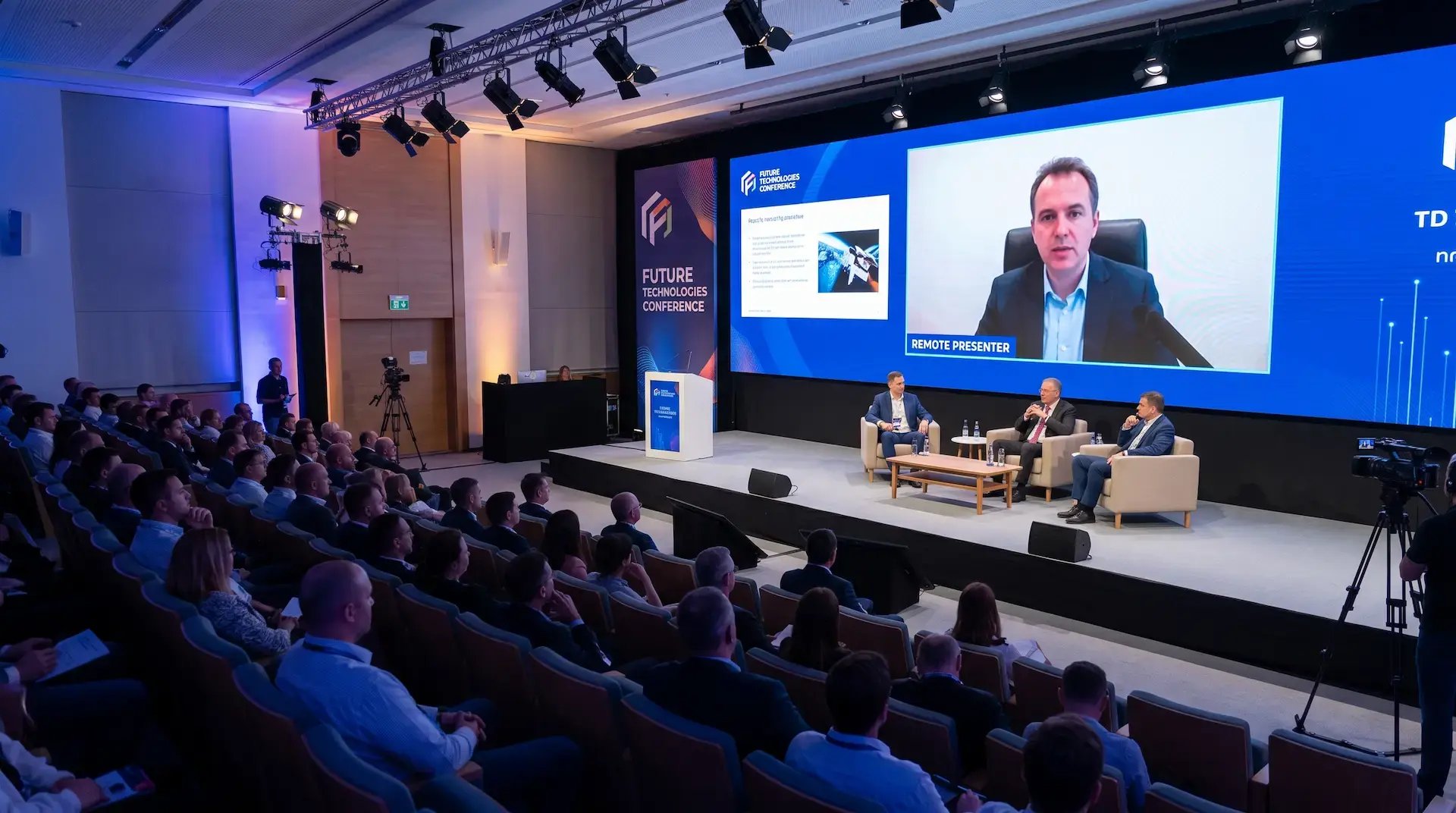 Hybrid event production setup with live audience and remote presenter on screen