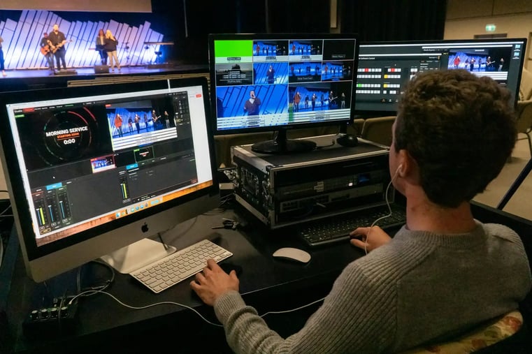 Production operator monitoring a multi-screen live-stream switcher during a broadcast