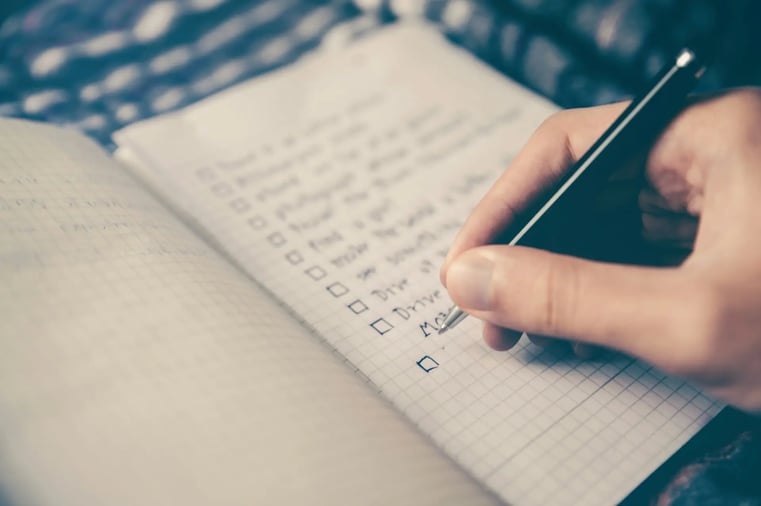 Planner writing a conference theme checklist by hand