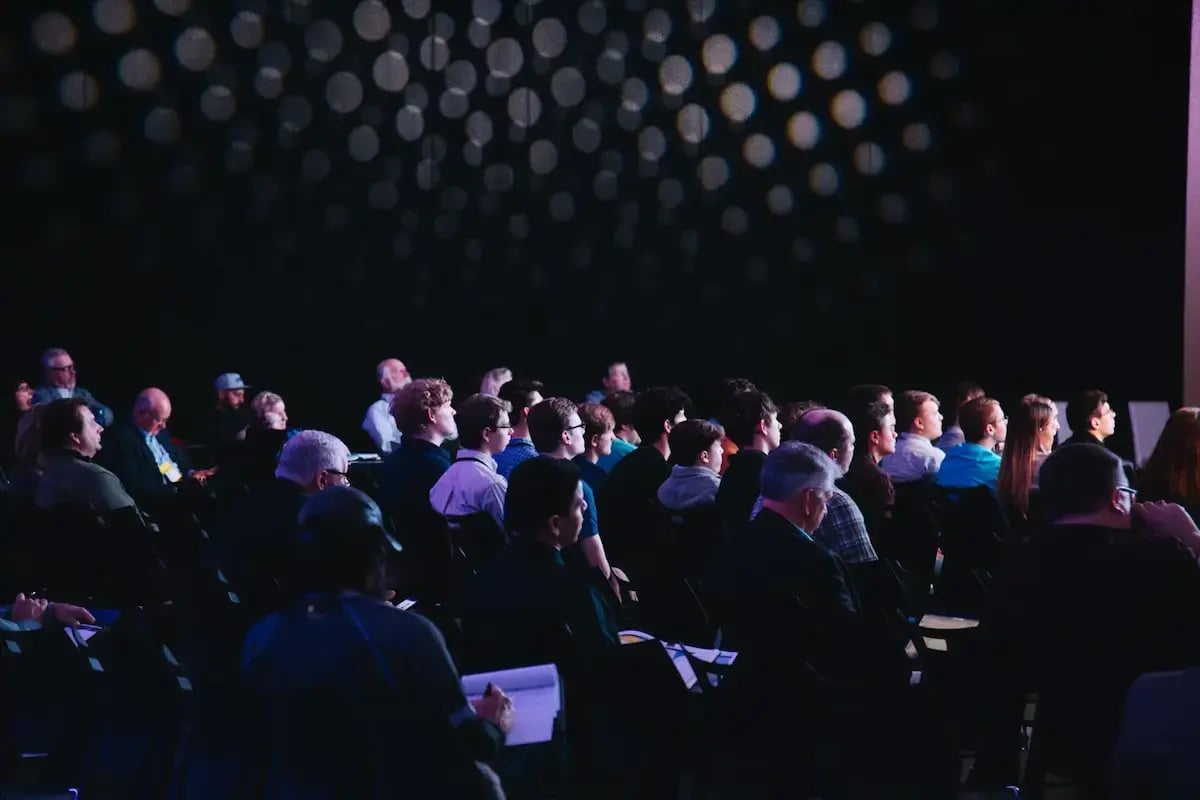 Audience seated in a darkened venue watching a live presentation
