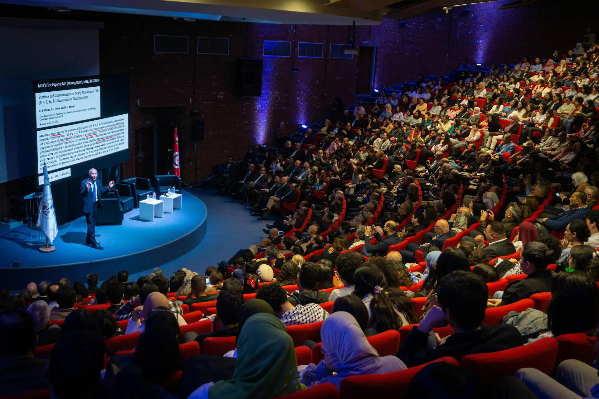 Speaker presenting to a full auditorium of seated conference attendees